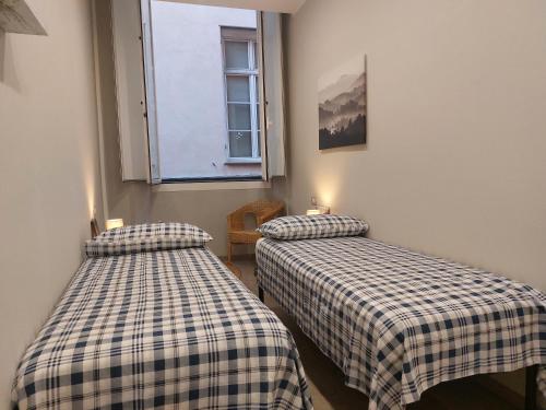 two twin beds in a room with a window at Appartamento Piazzetta La Maddalena in Savona