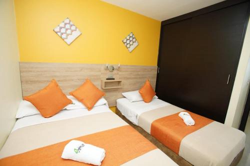 2 Betten in einem Zimmer mit Gelb- und Orangetönen in der Unterkunft Apartamento con piscina cerca al parque del café in Montenegro