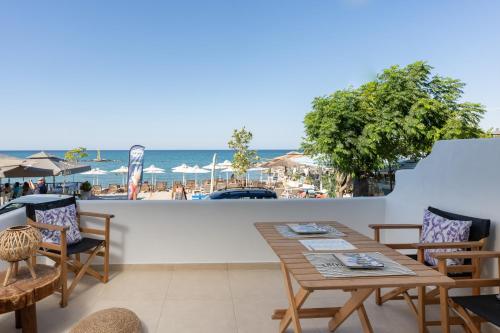 une terrasse avec une table et des chaises et la plage dans l'établissement Galazio Seaside Luxury Rooms & Coffee Shop, à Platamonas