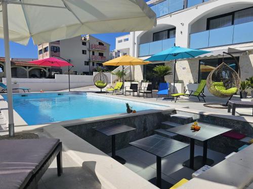 a swimming pool with tables and umbrellas on a building at The Luxury Apartments - Villa Havana in Novalja