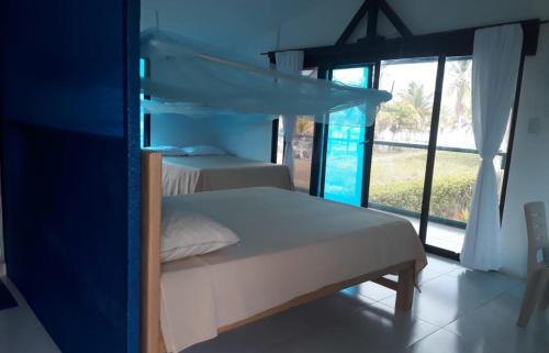 1 dormitorio con 2 camas y ventana grande en Cabaña RECUERDO Lodge, B & B, en Moñitos