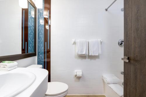 a white bathroom with a toilet and a sink at Regency Miami Airport by Sonesta in Miami