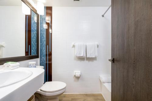 a white bathroom with a toilet and a sink at Regency Miami Airport by Sonesta in Miami