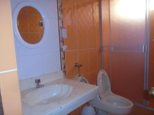 y baño con lavabo, aseo y espejo. en hostal andina joya, en Puno