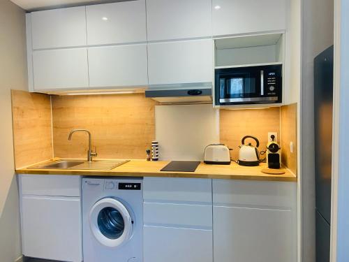 une cuisine avec un lave-linge et un micro-ondes dans l'établissement PWS Cannes Le Cosy Palm * Elegant 2P Climatisé!, à Cannes