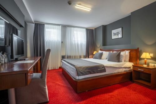 Dormitorio con cama, escritorio y TV en Hotel Astra, en Sarajevo