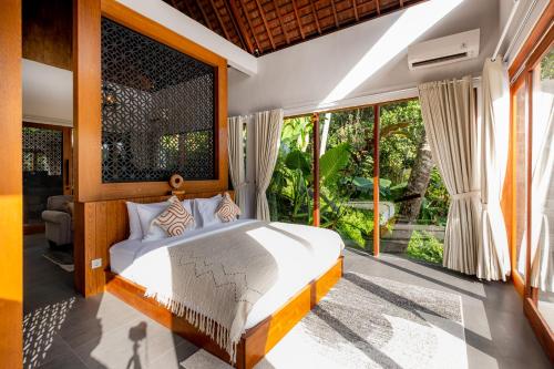 sypialnia z łóżkiem i dużym oknem w obiekcie LeRosa Valley Resort w mieście Ubud