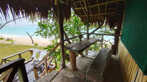 a wooden porch with a bench and chairs on the beach at Serenity Treehouse in Port Olry