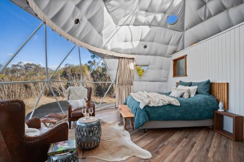 ein Schlafzimmer mit einem Bett in einem Zimmer mit großen Fenstern in der Unterkunft Scribbly Farm, Boutique Southern Highlands Accommodation in Joadja Creek