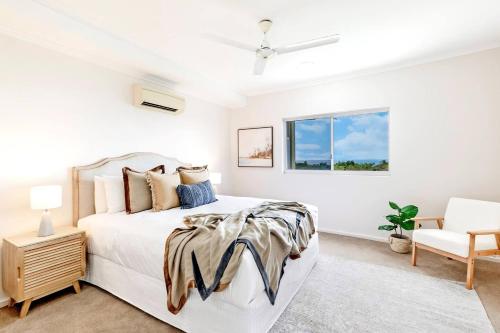 a white bedroom with a bed and a chair at Harbour Haven - A Parkside CBD Address in Larrakeyah