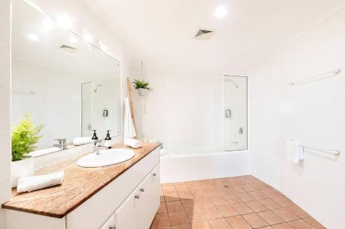 a white bathroom with a sink and a tub at Harbour Haven - A Parkside CBD Address in Larrakeyah