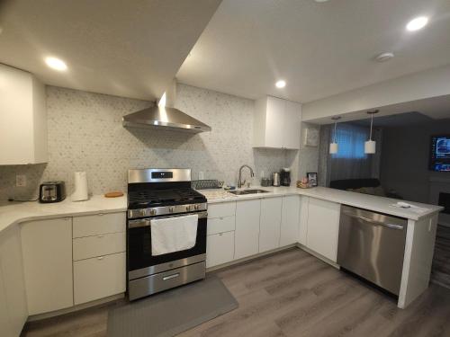 a kitchen with white cabinets and a stove top oven at Cozy 2 Bedroom Suite, Queen Beds, Near the Airport in Edmonton