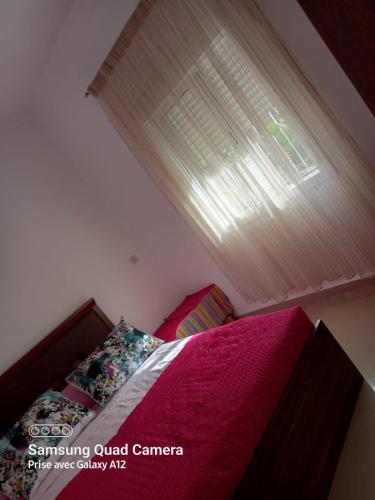 a bedroom with a bed with pink sheets and a window at Mekkad in Oued Laou