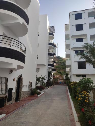 une allée entre deux bâtiments blancs avec balcon dans l'établissement Mekkad, à Oued Laou