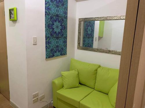 - un canapé vert dans une pièce avec un miroir dans l'établissement Grace Residences Taguig City, à Manille
