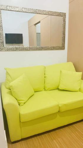 - un canapé jaune dans le salon dans l'établissement Grace Residences Taguig City, à Manille