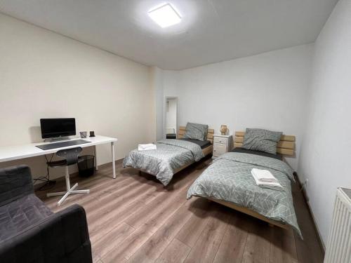 韋爾維耶的住宿－Appartement Verviers，一间卧室配有两张床和一张带电脑的书桌