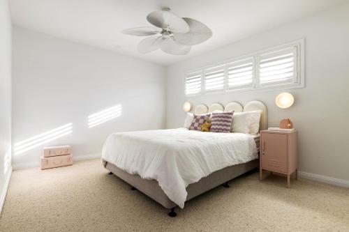 Coastal Haven في North Creek: غرفة نوم بيضاء مع سرير ومروحة سقف