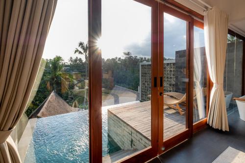 een kamer met een glazen deur en uitzicht op een zwembad bij LeRosa Valley Resort in Ubud