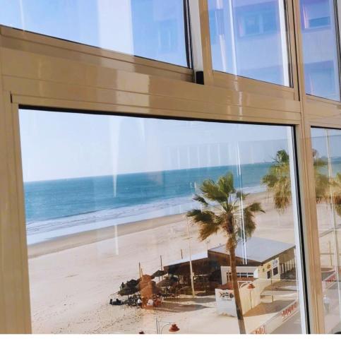 a view of a beach from a glass window at Quiero Cádiz in Cádiz