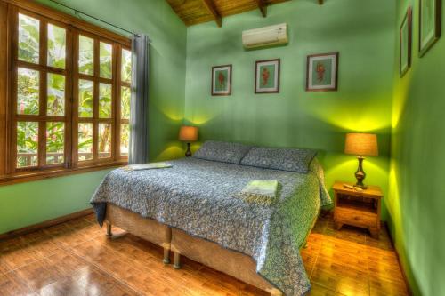 a bedroom with a bed in a green room at Beachfront Villa Sea Breeze w AC and POOL in Puerto Viejo