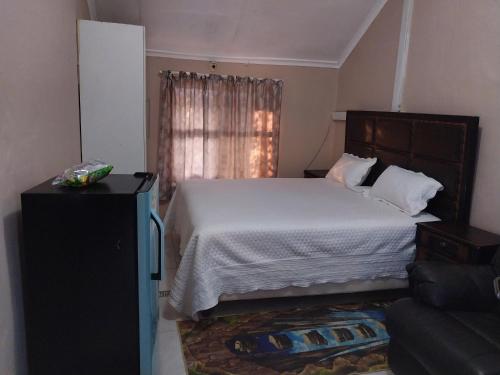 een slaapkamer met een bed, een bank en een raam bij WAKEUP FRESH GUEST HOUSE in Johannesburg