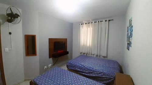 a bedroom with two beds and a tv at Apartamento na Praia Grande in Praia Grande