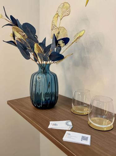 a blue vase with flowers sitting on a table with two glasses at Amalfi Coast Casa Ida in Vietri sul Mare