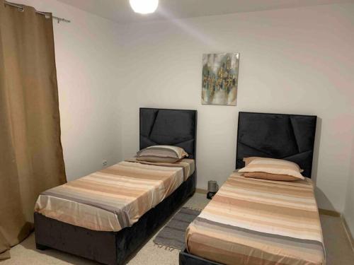 dos camas sentadas una al lado de la otra en una habitación en Appartement 5 lits climatisé salon 2chambres cuisine équipée SDB en Staoueli