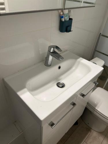 La salle de bains est pourvue d'un lavabo blanc et de toilettes. dans l'établissement Magnifique studio situé à 7min en métro de Paris, à Asnières-sur-Seine