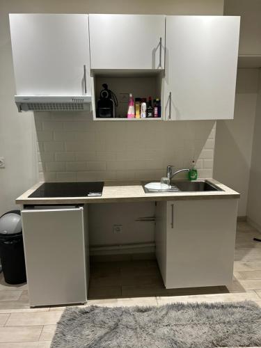 une cuisine avec des armoires blanches et un évier dans l'établissement Magnifique studio situé à 7min en métro de Paris, à Asnières-sur-Seine
