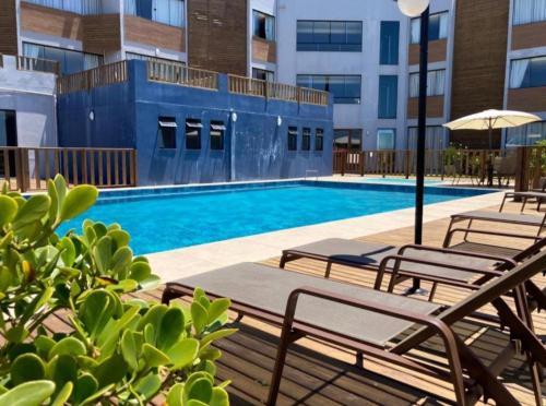 - une piscine avec des chaises et un parasol dans un bâtiment dans l'établissement Loft 320 - Residence Farol, à Laguna