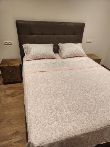 ein großes Bett mit einem braunen Kopfteil und zwei Kissen in der Unterkunft Gardénia la perle de Martil in Martil