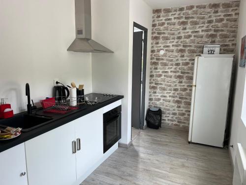 a kitchen with a white refrigerator and a brick wall at Nid douillet à La Bresse in La Bresse