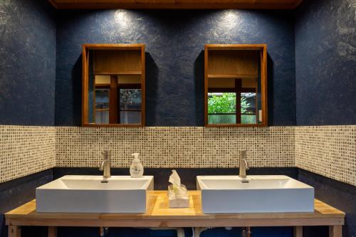 two sinks in a bathroom with two mirrors at うみの図書館 in Sanuki