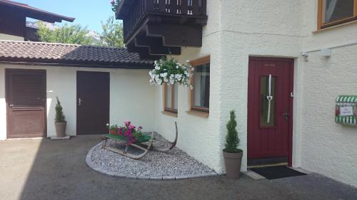 una casa con una puerta roja y flores delante de ella en Haus Alpenrose, en Waidring
