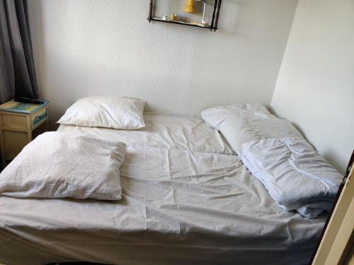 een ongeëvenaard bed met witte lakens en kussens bij Studette à 100m de la plage in Saint-Jean-de-Monts