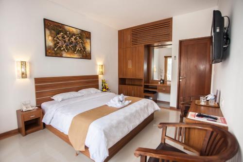 a bedroom with a large bed and a television at Satriya Cottages in Kuta