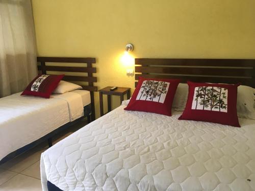 1 dormitorio con 2 camas y almohadas rojas en Casa Josefa Hotel, en Santiago Atitlán