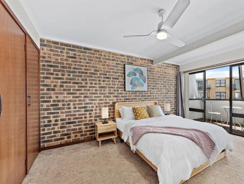 a bedroom with a brick wall and a bed at The Entrance 2Beds Holiday House in The Entrance