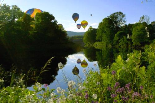 two hot air balloons flying over a river at Quechee Condo in Quechee