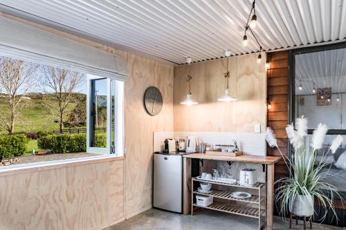 a kitchen with a refrigerator and a counter with a window at Flaxpod Cabin in Raglan