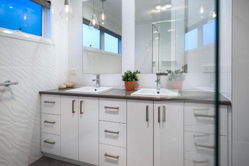 a white bathroom with two sinks and a mirror at Quartz Retreat in Daylesford