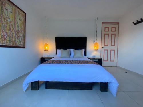 a bedroom with a large white bed with two lamps at Mahalo Hostel in Salento