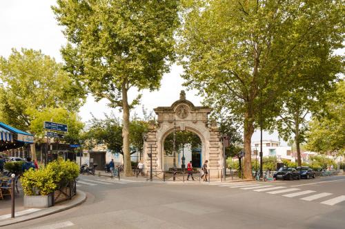 un arco en medio de una calle con árboles en Sonder Quintinie, en París