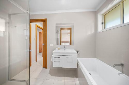 麥覺理港的住宿－ULTIQA Village Resort，带浴缸、水槽和淋浴的浴室