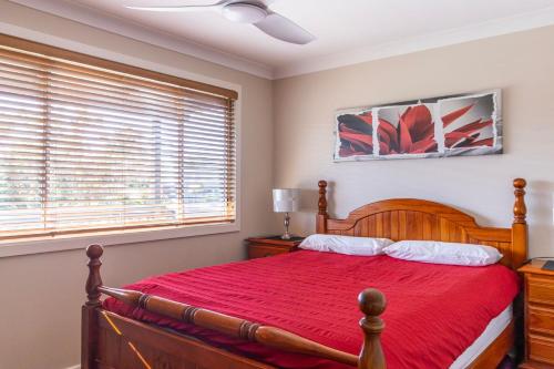 1 dormitorio con cama de madera y colcha roja en The Perfect Holiday Home en Sussex inlet
