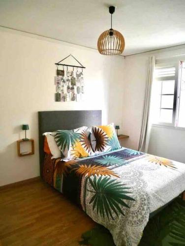 una camera da letto con un letto con un piumone colorato di Chez Steph chaleureux & cosy T3 a Fort-de-France