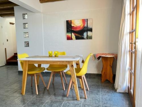 a dining room with a table and yellow chairs at Casa del Pinar-Plottier-Diario Semanal Mensual-La Mejor Ubicación-Garaje Cerra do in Plottier