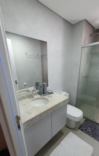 a bathroom with a sink and a toilet and a mirror at Flat em Boa Viagem - Edifício Rooftop 470 in Recife